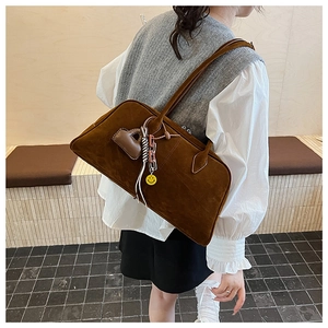 Detail der dunkelbraunen Wildleder-Schultertasche mit Retro-Anhängern und Textur