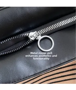 Detail view of smooth black leather bag featuring silver round ring metal zipper and striped lining