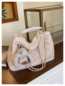 Dettaglio della borsa tote in ecopelliccia rosa con manici in pelle e catena oro