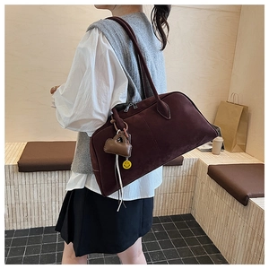 Details einer burgunderroten Wildledertasche mit Doppel-Reißverschluss und Anhängern