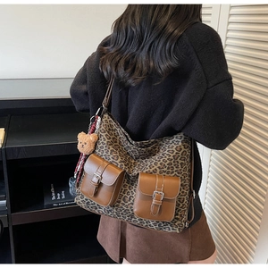 Close-up of leopard print crossbody bag with dual front pockets and a cute bear charm