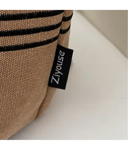 Detailed macro view of khaki canvas fabric with embroidered stripes and a brand side label