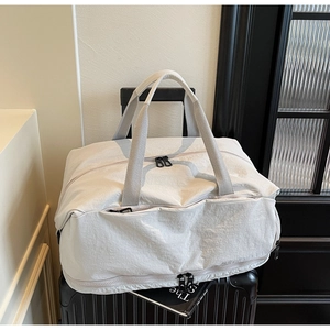 Detail view of large capacity cream travel bag with dedicated shoe compartment on luggage