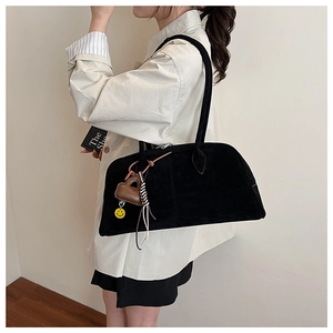 Detail einer schwarzen Wildleder-Boston-Tasche mit Leder-Herzanhänger und Quastendeko