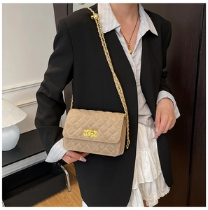 Detail of beige quilted crossbody bag with gold chain strap and metal ball slider on model