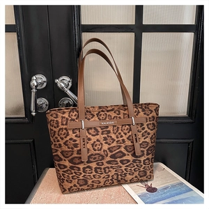 Dettaglio della borsa tote leopardata con manici in pelle marrone e logo argentato