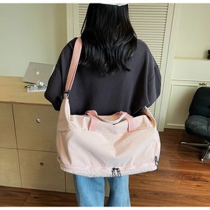 Detail of pink travel bag with separate bottom shoe compartment and adjustable shoulder strap