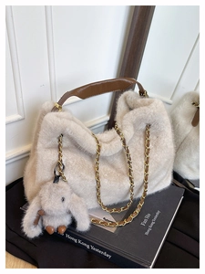 Dettaglio della borsa in ecopelliccia beige con manici in pelle marrone e ciondolo a coniglio