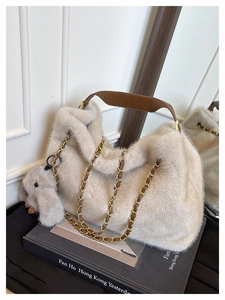 Dettaglio borsa hobo in peluche bianco sporco con catena dorata e ciondolo a forma di coniglio
