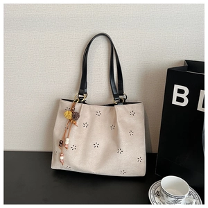 Détail du motif floral découpé au laser sur le cabas en daim beige avec lanière