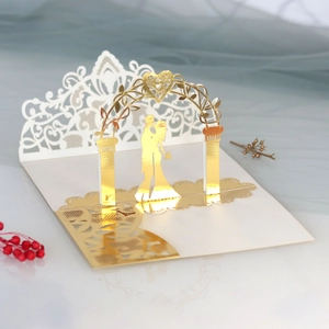 Detail of 3D laser-cut wedding invitation featuring golden arch and couple silhouette