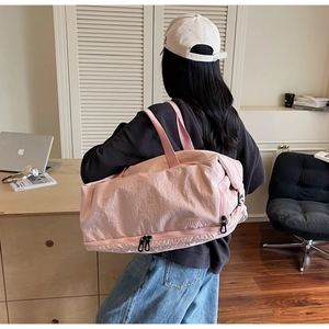 Pink travel bag with separate bottom shoe compartment shown on a female model