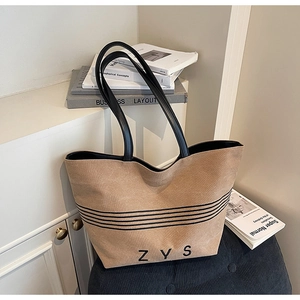 Detail of camel canvas tote bag showing black stripes, ZYS lettering, and leather straps