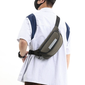 Detail view of dark green crossbody bag with safety reflective strip on model's back