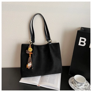 Détail du sac cabas en daim noir avec motifs étoiles embossés et pompon perlé coloré