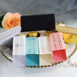 Elegant laser-cut rectangular wedding favor boxes in various colors on a glass tray