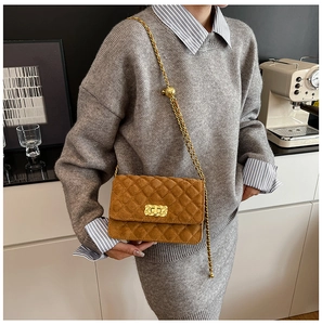 Detail of a brown quilted suede crossbody bag featuring gold metal chain and rectangular lock