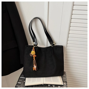 Détails de motifs floraux ajourés et pendentif ethnique sur un sac cabas en suède noir