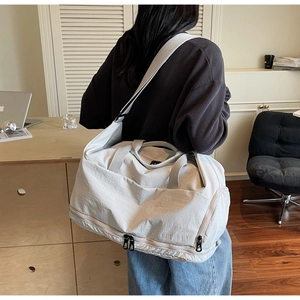Detail of light beige travel bag featuring a separate bottom shoe compartment and shoulder strap