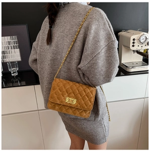 Close-up of caramel quilted suede crossbody bag with vintage gold turn-lock and chain strap