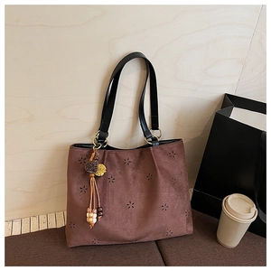Détail du motif floral ajouré sur le sac cabas en daim marron avec pendentif bohème