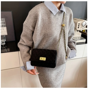 Close-up of quilted chain crossbody bag with golden twist lock on a model in daily life