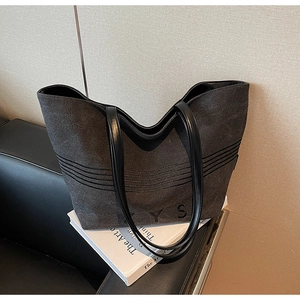 Macro view of charcoal canvas tote bag featuring leather handles and stitched details