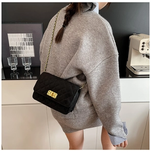 Detailed close-up of a black quilted chain bag with a gold metal twist-lock and shoulder strap