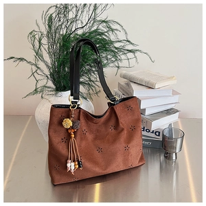 Détail du cabas en daim marron avec motifs floraux découpés au laser et pompon boho