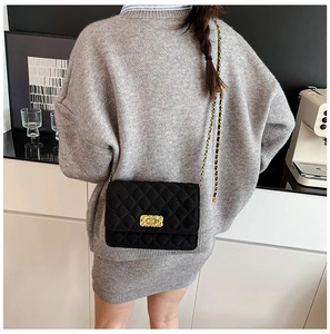 Model wearing a black quilted crossbody bag with gold chain strap and vintage metal lock