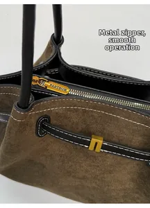 Close-up of smooth gold metal zipper and suede texture on large shoulder tote bag