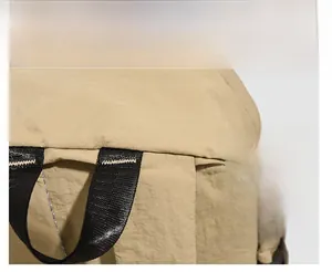 Detail of the durable nylon handle and reinforced stitching on the khaki backpack