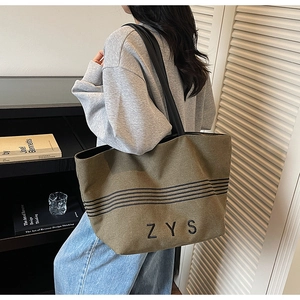 Detail of olive green canvas tote bag with black stripes and ZYS embroidery