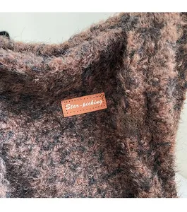 Detail van de fleece emmertas met donkerbruine teddy-stof en leren logo-label erop