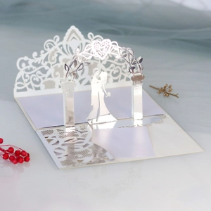 Detailed laser-cut 3D wedding invitation featuring a bride and groom under a floral archway
