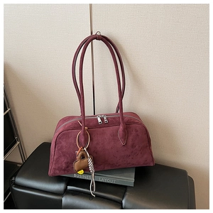 Detail der burgunderroten Wildleder-Bowlingtasche mit Doppelriemen und Smiley-Anhänger
