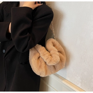 Detailed view of camel faux fur crossbody bag with elegant gold chain strap on black coat