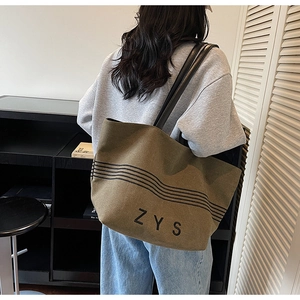 Detail of olive green canvas tote bag showing black stripes and ZYS logo lettering