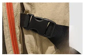 Macro shot of durable black plastic buckle and vibrant orange zipper on khaki backpack
