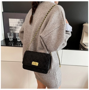 Close-up of black quilted crossbody bag with gold chain strap worn by a model