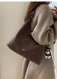 Detail of vintage brown textured leather shoulder bag with logo and puppy charm accessory