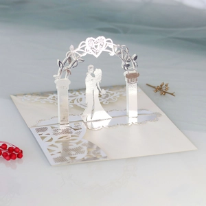 Detail of 3D laser-cut wedding invitation showing a couple kissing under a heart archway