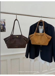 Close-up of minimalist retro suede tote bag with golden lock and embossed brand logo