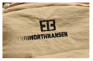 Macro detail of khaki waterproof nylon fabric with black precision embroidered logo and text