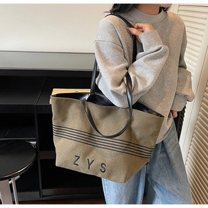Detail of olive green canvas tote bag with black stripes and ZYS embroidery