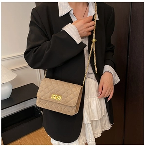 Detailed close-up of a beige quilted crossbody bag with a gold chain and turn-lock closure