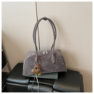 Detailansicht der grauen Wildledertasche mit silbernen Reißverschlüssen und Anhänger
