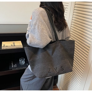 Close-up of a striped canvas tote bag with ZYS embroidery and black leather straps