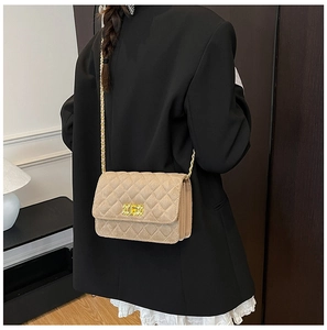 Detail showing beige suede quilted crossbody bag with gold chain strap and square turn lock