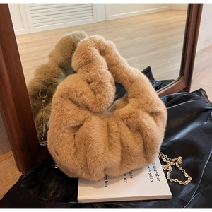 Close-up of khaki plush cloud bag with gold chain and knotted handle on black silk